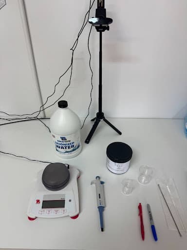 Lab bench setup with camera on tripod, scale, pipette, and equipment